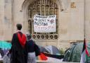 Graduating students pass an encampment protest over the Gaza conflict on the grounds of Cambridge University (Joe Giddens/ PA)