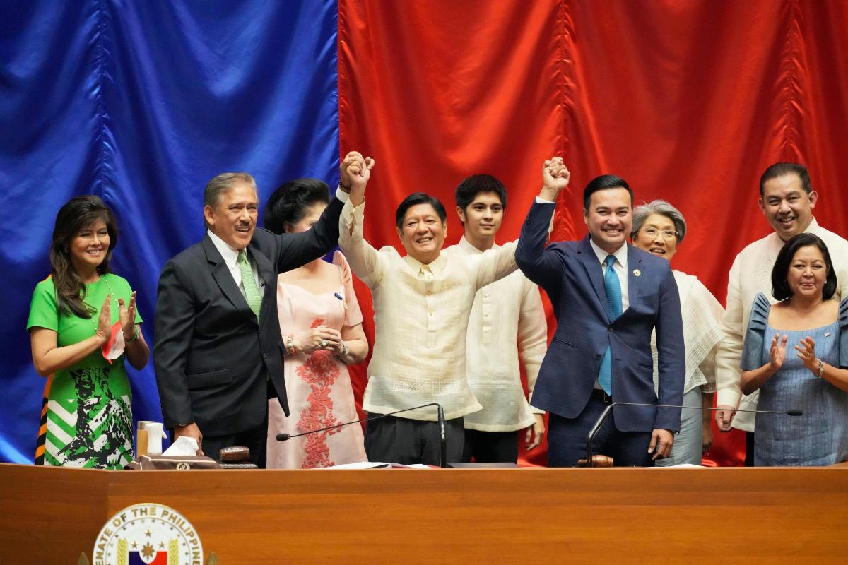 Ferdinand Marcos Jr, centre, raises hands