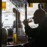 A man drinks a pint of lager in a pub