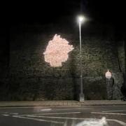 The Queen's head is projected on the castle wall at night.