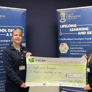 Karen Bulman (left), Team Manager for Vocational and Learning Skills, is pictured presenting cheque to Bridget Harpwood (right), Hywel Dda Health Charities Fundraising Officer. Picture: Ceredigion County Council.
