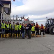 Cardigan RNLI lifeboat operations manager Pete Austin receives the donation from Ferwig Friends as volunteer crew members look on.