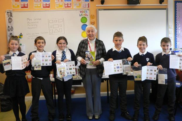 Children from Mary Immaculate School showing their first stamp albums, and helping Erene Grieve celebrate her 500th school visit.